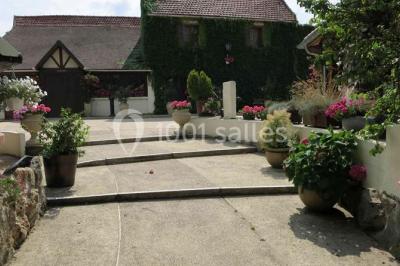 Arrangements floraux sur des supports en bois disposés sur une table recouverte d'une nappe blanche devant un mur en pierre.