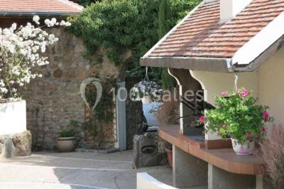 Arrangements floraux sur des supports en bois disposés sur une table recouverte d'une nappe blanche devant un mur en pierre.