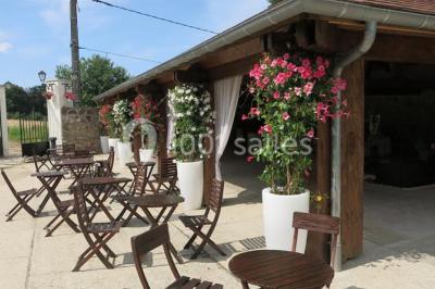 Arrangements floraux sur des supports en bois disposés sur une table recouverte d'une nappe blanche devant un mur en pierre.