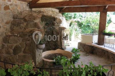 Arrangements floraux sur des supports en bois disposés sur une table recouverte d'une nappe blanche devant un mur en pierre.