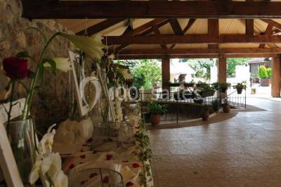 Arrangements floraux sur des supports en bois disposés sur une table recouverte d'une nappe blanche devant un mur en pierre.