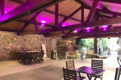 Arrangements floraux sur des supports en bois disposés sur une table recouverte d'une nappe blanche devant un mur en pierre.