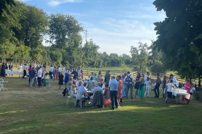 Groupe de personnes rassemblées dans un jardin verdoyant par une journée ensoleillée.