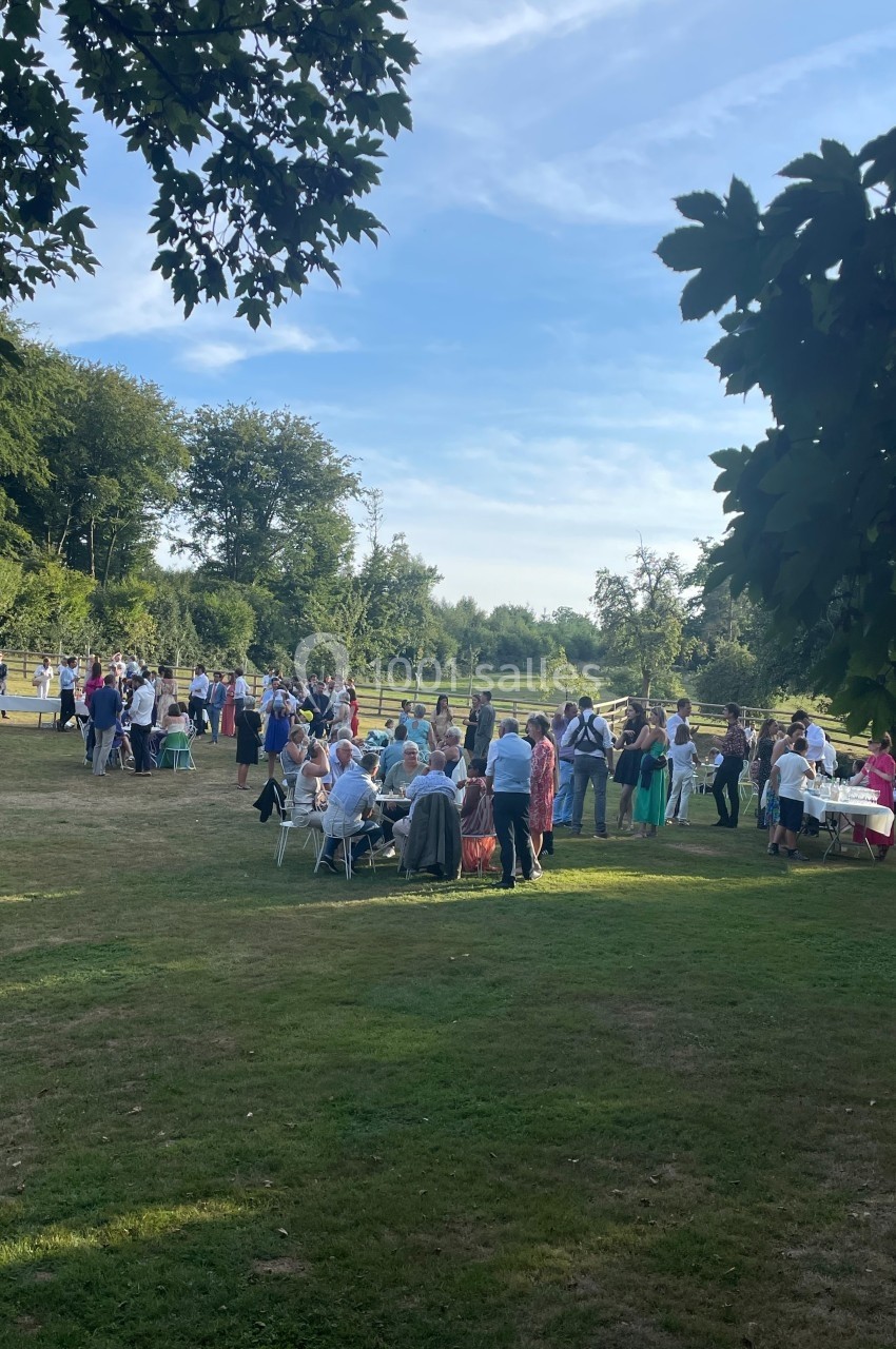 Groupe de personnes rassemblées dans un jardin verdoyant par une journée ensoleillée.