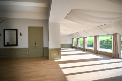 Façade en pierre d'une maison avec toit en tuiles, vue partiellement à travers des branches fleuries au premier plan.