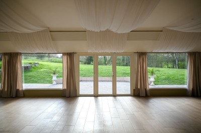 Façade en pierre d'une maison avec toit en tuiles, vue partiellement à travers des branches fleuries au premier plan.