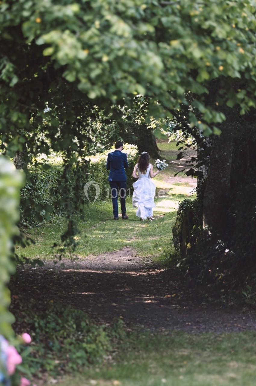 Un couple marche sur un sentier verdoyant, entouré d'arbres et de végétation.