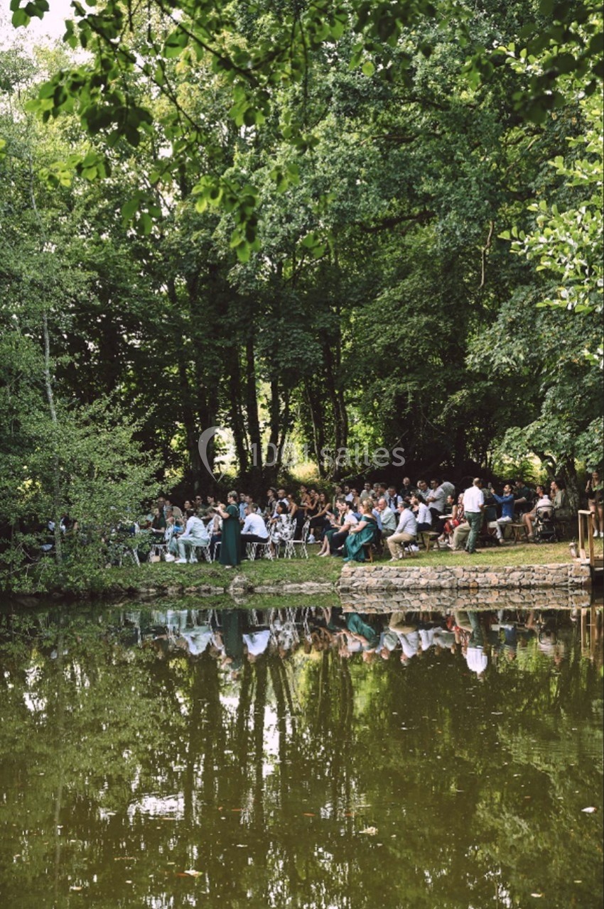 Un groupe de personnes assises en plein air près d'un étang entouré d'arbres.