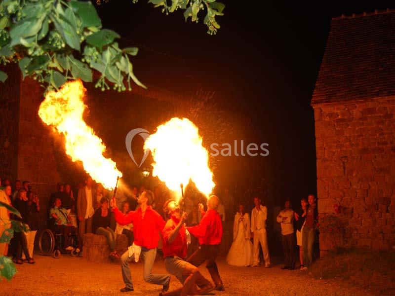 Des cracheurs de feu en chemises rouges réalisant une performance nocturne devant un public en extérieur.