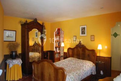 Chambre avec lit double, armoire en bois, murs jaunes, lampes de chevet et accès partiel à une salle de bain.