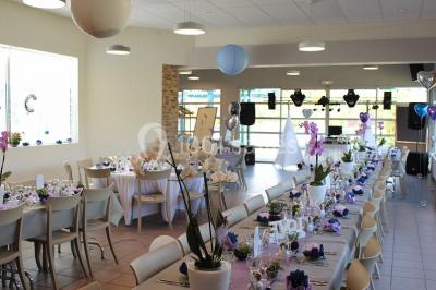 Une personne joue au tennis sur un court extérieur entouré d'arbres, sous un ciel dégagé.