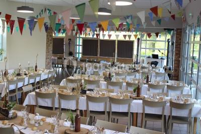 Une personne joue au tennis sur un court extérieur entouré d'arbres, sous un ciel dégagé.