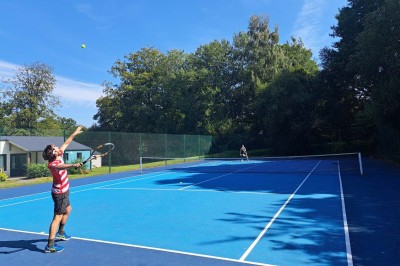 Salle de bain moderne avec lavabo, miroir, toilettes suspendues et douche en arrière-plan.