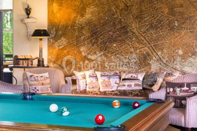 Une femme reçoit un massage sur une table dans une pièce chaleureuse avec des rideaux, des bougies et une lumière tamisée.