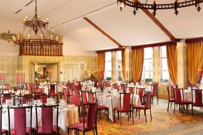 Une femme reçoit un massage sur une table dans une pièce chaleureuse avec des rideaux, des bougies et une lumière tamisée.