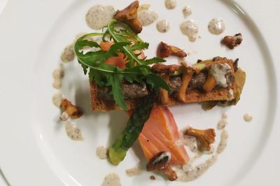 Une femme reçoit un massage sur une table dans une pièce chaleureuse avec des rideaux, des bougies et une lumière tamisée.