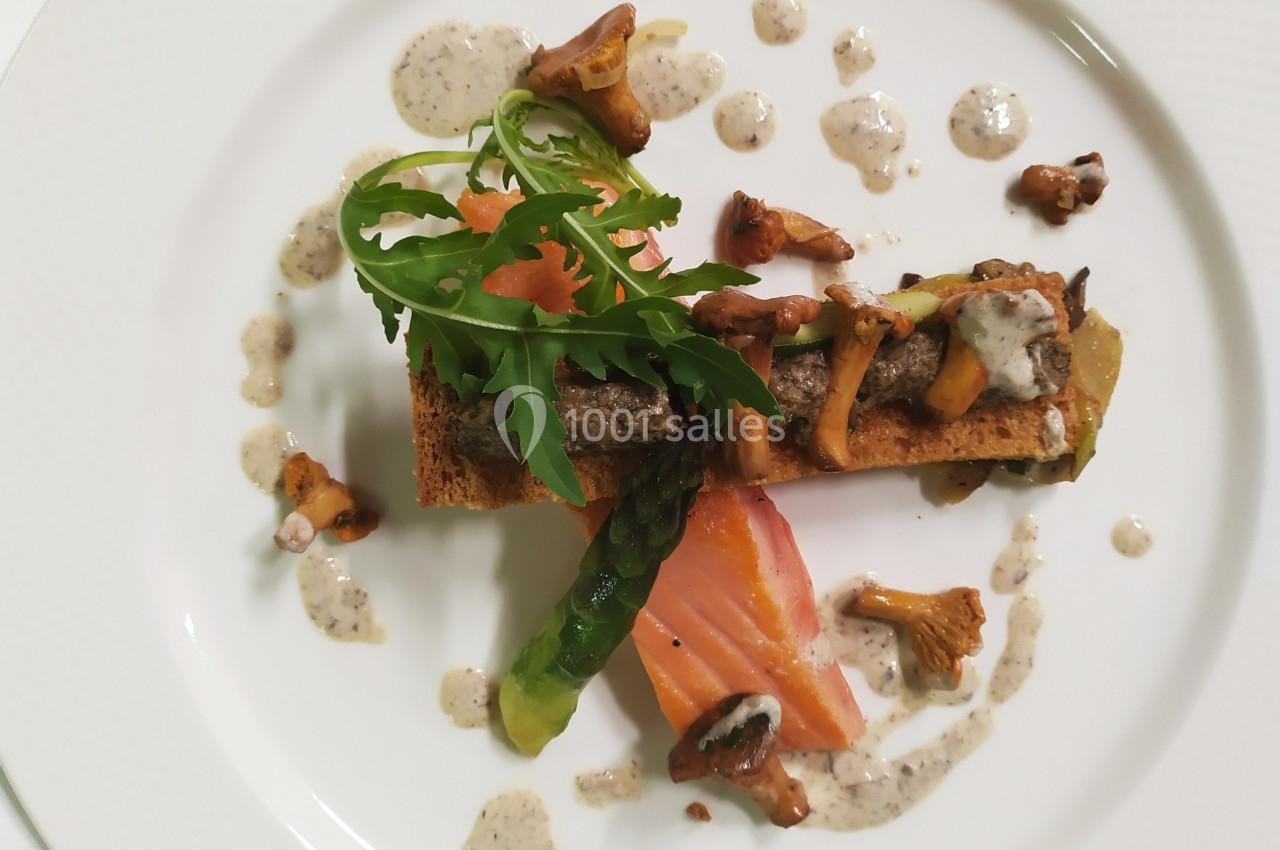 Assiette gastronomique avec toast garni de champignons, saumon fumé, roquette et sauce disposée en gouttelettes.