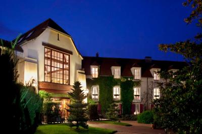 Une femme reçoit un massage sur une table dans une pièce chaleureuse avec des rideaux, des bougies et une lumière tamisée.