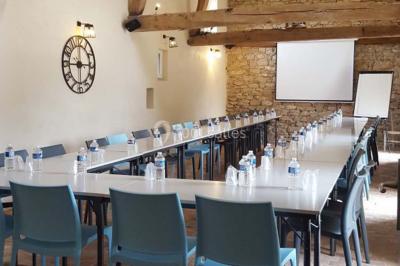 Façade d'une grande maison en pierre éclairée la nuit, entourée d'un jardin sombre et d'annexes.
