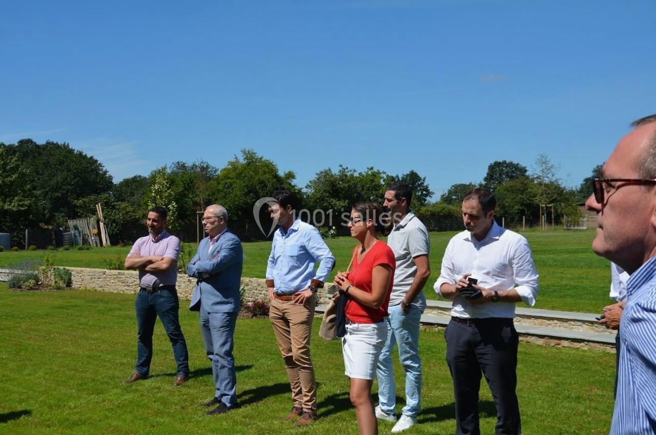 Un groupe de personnes debout sur une pelouse, discutant sous un ciel dégagé.