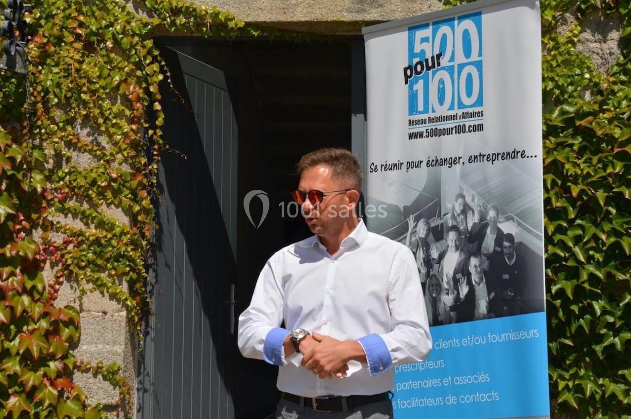 Un homme en chemise blanche parle devant une porte ouverte, près d'une bannière d'un réseau professionnel.
