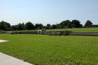 Façade d'une grande maison en pierre éclairée la nuit, entourée d'un jardin sombre et d'annexes.
