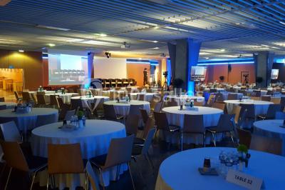 Salle de réunion avec tables disposées en U, bouteilles d'eau et gobelets, panneau d'information en arrière-plan.