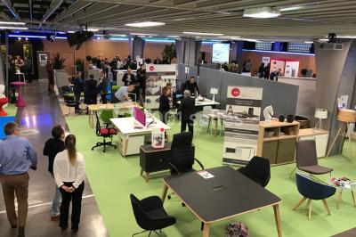 Salle de réunion avec tables disposées en U, bouteilles d'eau et gobelets, panneau d'information en arrière-plan.