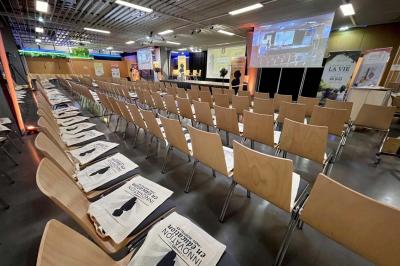 Salle de réunion avec tables disposées en U, bouteilles d'eau et gobelets, panneau d'information en arrière-plan.