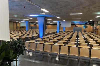 Salle de réunion avec tables disposées en U, bouteilles d'eau et gobelets, panneau d'information en arrière-plan.