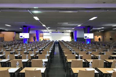 Salle de réunion avec tables disposées en U, bouteilles d'eau et gobelets, panneau d'information en arrière-plan.