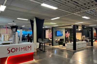 Salle de réunion avec tables disposées en U, bouteilles d'eau et gobelets, panneau d'information en arrière-plan.