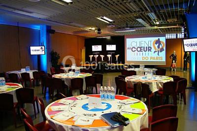 Salle de réunion avec tables disposées en U, bouteilles d'eau et gobelets, panneau d'information en arrière-plan.