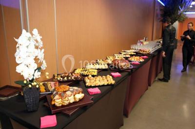 Salle de réunion avec tables disposées en U, bouteilles d'eau et gobelets, panneau d'information en arrière-plan.