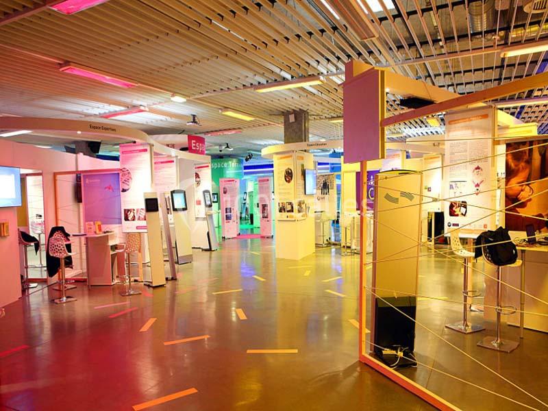 Espace d'exposition intérieur avec panneaux informatifs, mobilier moderne et éclairage coloré.