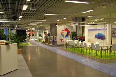 Salle de réunion avec tables disposées en U, bouteilles d'eau et gobelets, panneau d'information en arrière-plan.