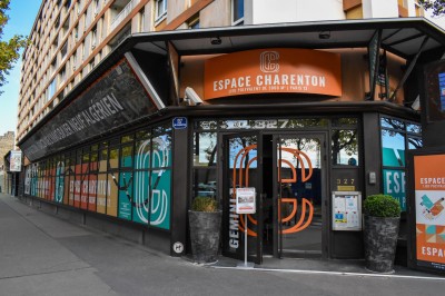 Salle de réunion avec tables disposées en U, bouteilles d'eau et gobelets, panneau d'information en arrière-plan.