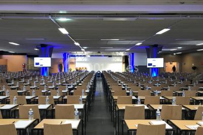 Salle de réunion avec tables disposées en U, bouteilles d'eau et gobelets, panneau d'information en arrière-plan.
