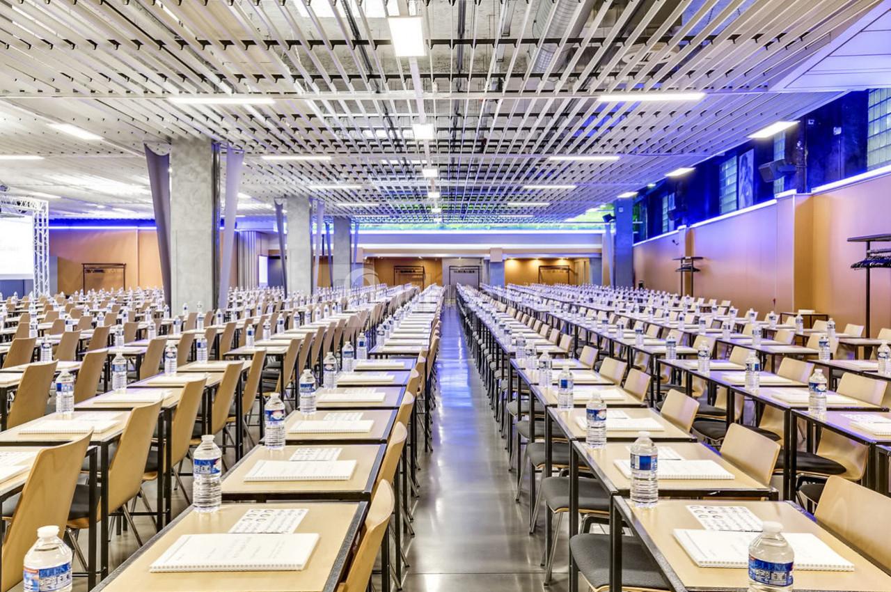 Salle de conférence spacieuse avec de longues rangées de tables et chaises, préparées avec des documents et des bouteilles d…