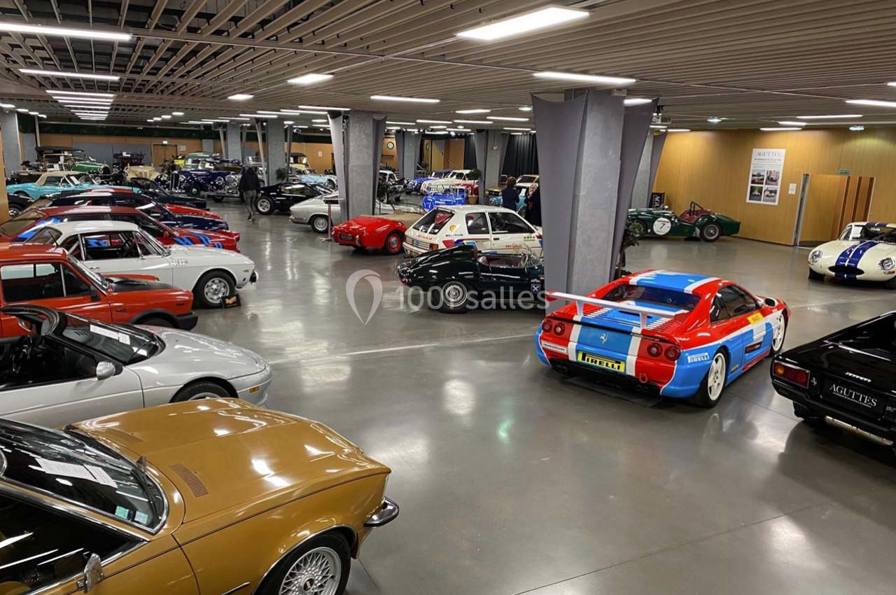 Salle d'exposition avec plusieurs voitures de collection de différentes époques, alignées dans un espace éclairé.