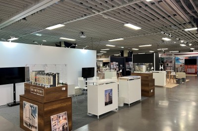 Salle de réunion avec tables disposées en U, bouteilles d'eau et gobelets, panneau d'information en arrière-plan.