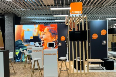 Salle de réunion avec tables disposées en U, bouteilles d'eau et gobelets, panneau d'information en arrière-plan.