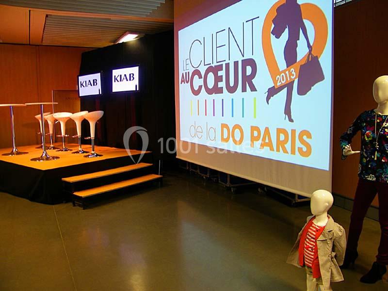 Mannequins et scène avec écran affichant un visuel d'événement dans une salle de conférence.