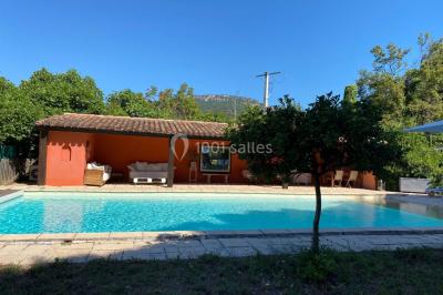 Terrain de pétanque ensoleillé entouré d'arbres et de végétation dans un jardin.