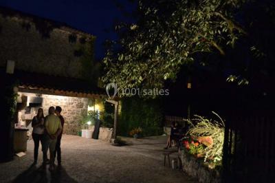Arbre en fleurs roses devant un bâtiment en pierre avec une porte en bois, sous un ciel bleu clair.