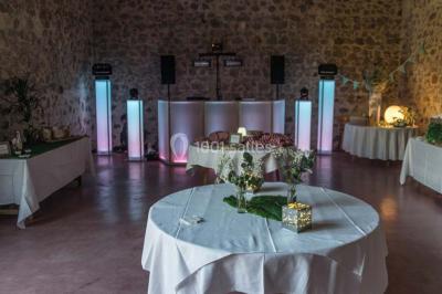 Arbre en fleurs roses devant un bâtiment en pierre avec une porte en bois, sous un ciel bleu clair.