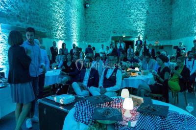 Arbre en fleurs roses devant un bâtiment en pierre avec une porte en bois, sous un ciel bleu clair.