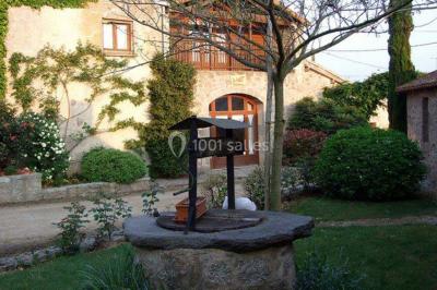 Arbre en fleurs roses devant un bâtiment en pierre avec une porte en bois, sous un ciel bleu clair.