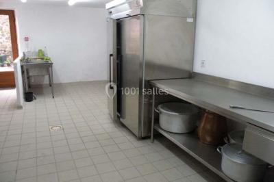 Arbre en fleurs roses devant un bâtiment en pierre avec une porte en bois, sous un ciel bleu clair.