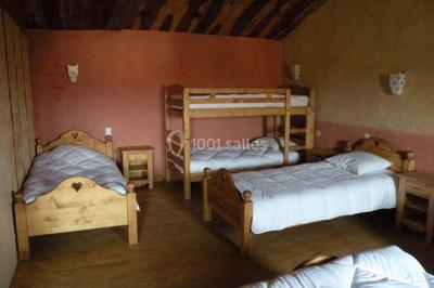 Arbre en fleurs roses devant un bâtiment en pierre avec une porte en bois, sous un ciel bleu clair.